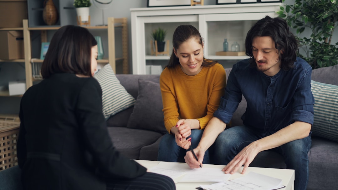 three-people-sitting-on-a-couch-looking-at-a-piece-of-paper-bmhnmnjxr98